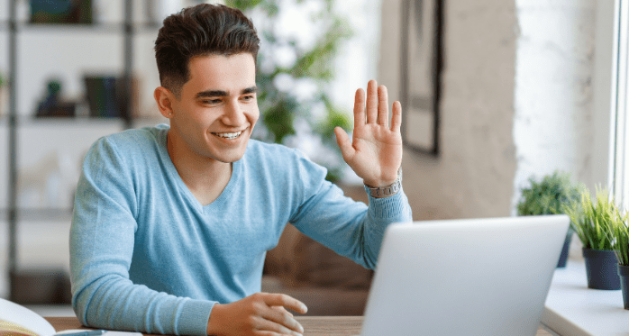 young man waving at laptop